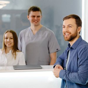 Happy patient standing at dental office front desk